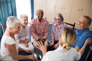 Cheerful seniors sitting with female doctor on chairs